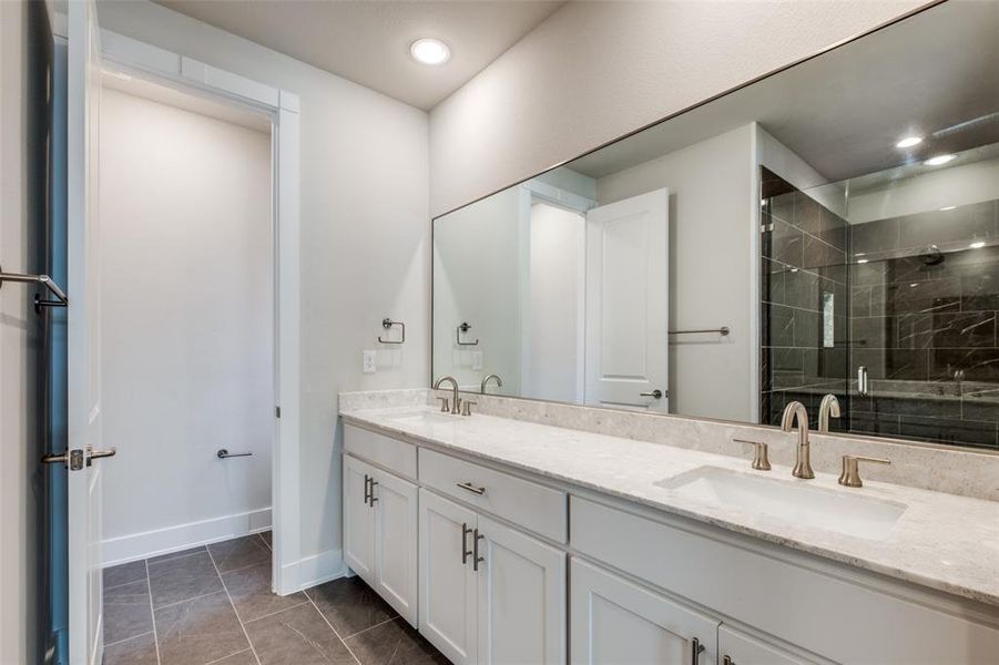 Bathroom featuring duel sink vanities, tile floors, and a shower with shower door