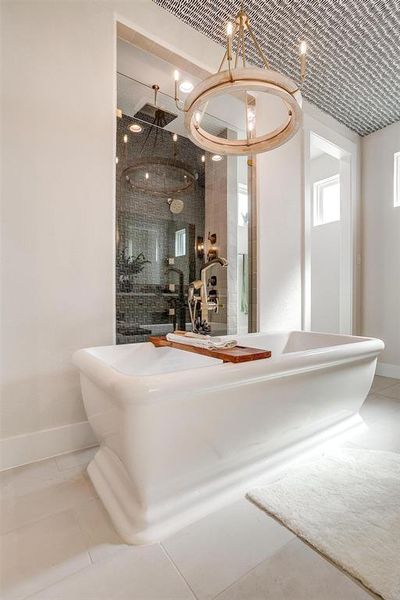 Bathroom with a freestanding tub, light tile patterned floors, a shower stall, and a chandelier