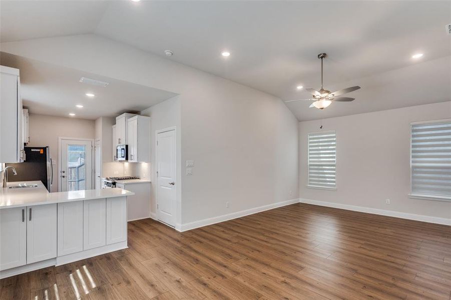 Kitchen featuring vaulted ceiling, white cabinets, open floor plan, plenty of natural light, and light wood-style flooring Kitchen featuring vaulted ceiling, white cabinets, open floor plan, plenty of natural light, and light wood-style flooring