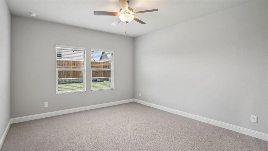 Carpeted spare room with baseboards and a ceiling fan