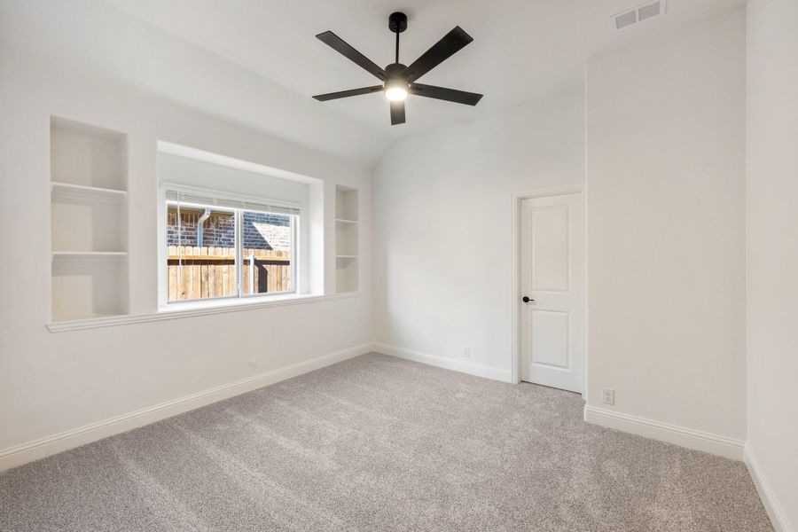 Empty bedroom with gray carpet, built-in shelves, vaulted ceiling, and black ceiling fan Empty bedroom with gray carpet, built-in shelves, vaulted ceiling, and black ceiling fan