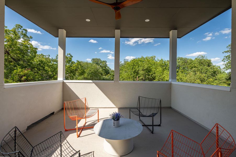 A covered balcony overlooks lush treetop views under a bright blue sky. A covered balcony overlooks lush treetop views under a bright blue sky.