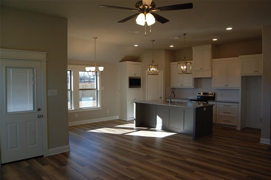 Kitchen with stainless steel appliances, dark hardwood / wood-style floors, an island with sink, and sink