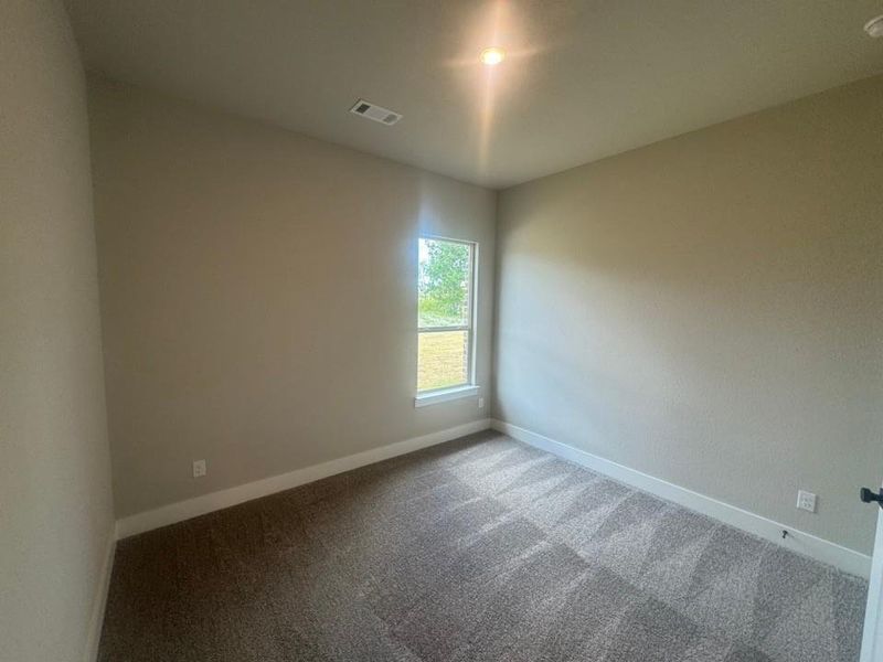Neutral-toned interior with patterned carpet flooring, a single window, recessed lighting, and white baseboards