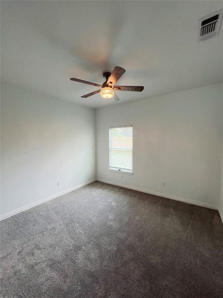 Spare room with dark carpet, visible vents, baseboards, and ceiling fan Spare room with dark carpet, visible vents, baseboards, and ceiling fan