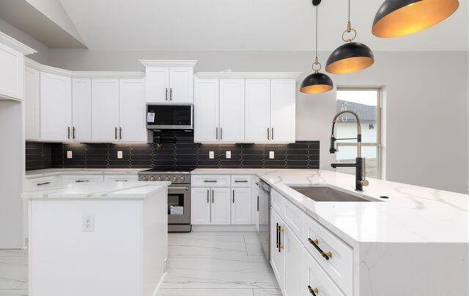 Modern kitchen featuring white cabinetry, a black subway tile backsplash, and light-toned countertops