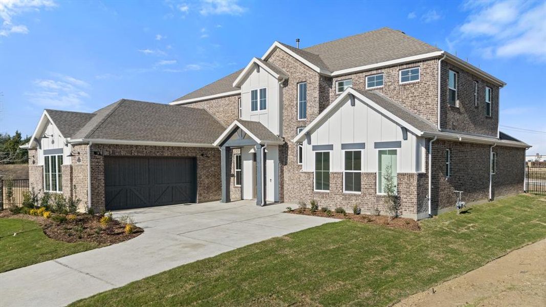 Craftsman inspired home featuring brick siding, an attached garage, board and batten siding, and concrete driveway