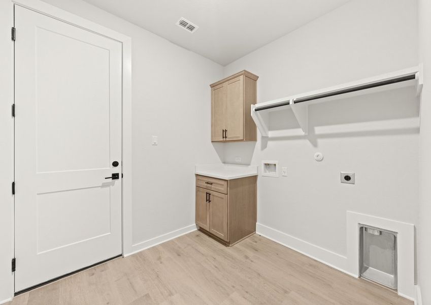 The laundry room has cabinets and a counter for additional convenience.