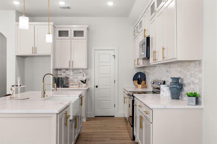 Kitchen featuring sink, appliances with stainless steel finishes, white cabinetry, light stone counters, and decorative light fixtures