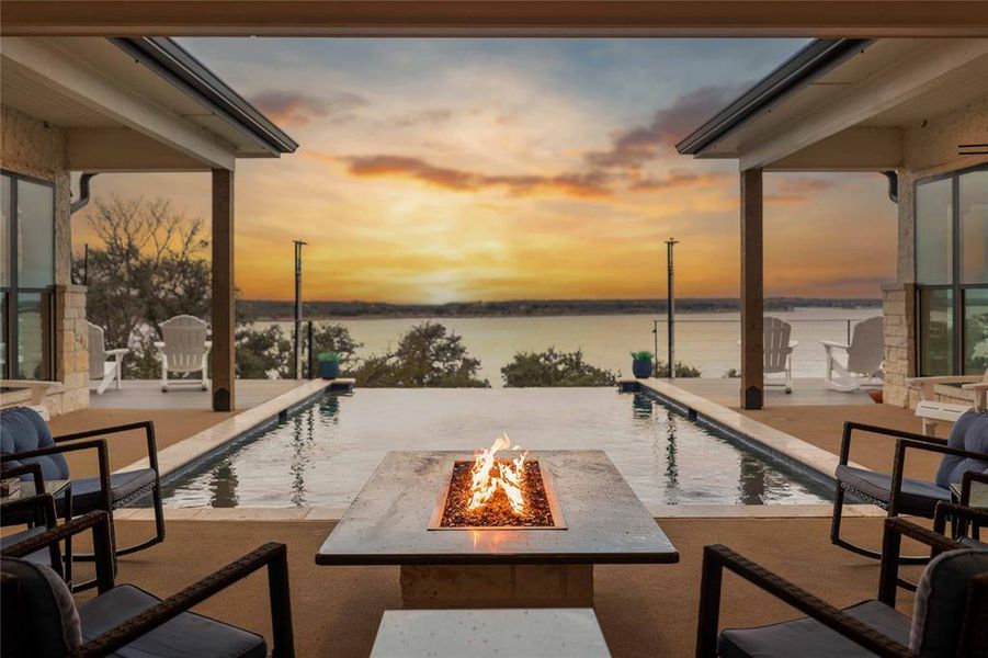Patio terrace at dusk with a patio area, a water view, an outdoor pool, and a fire pit