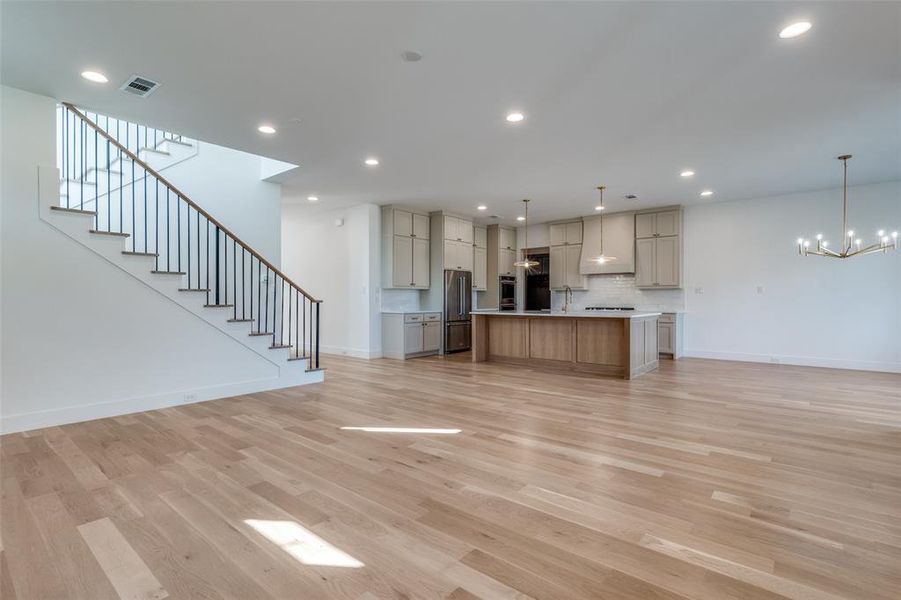 Unfurnished living room featuring an inviting chandelier and light hardwood / wood-style flooring