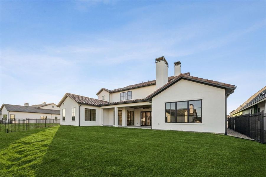 Rear view of house with a ceiling fan, a fenced backyard, a chimney, and stucco siding Rear view of house with a ceiling fan, a fenced backyard, a chimney, and stucco siding