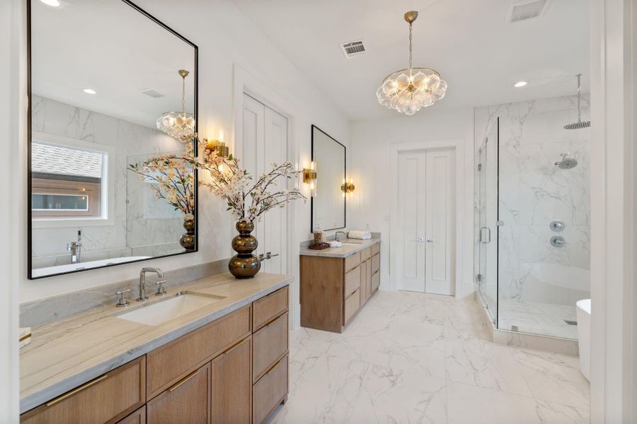 The spa-inspired primary bath features dual vanities with custom cabinetry, quartz countertops, and designer lighting, creating a refined and functional space.