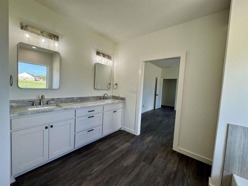 Full bathroom with double vanity and dark wood-style flooring Full bathroom with double vanity and dark wood-style flooring
