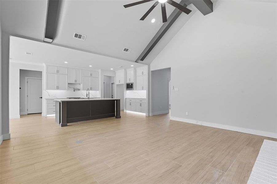 Unfurnished living room featuring high vaulted ceiling, beamed ceiling, recessed lighting, wood tiled floors, and a ceiling fan Unfurnished living room featuring high vaulted ceiling, beamed ceiling, recessed lighting, wood tiled floors, and a ceiling fan