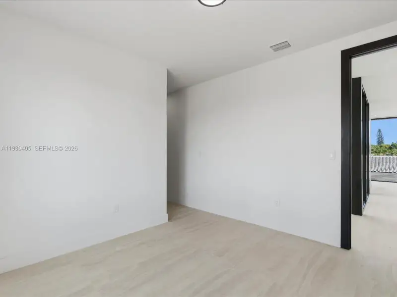 Interior space featuring neutral wall paint, wood-finish flooring, and dark-toned door trim Interior space featuring neutral wall paint, wood-finish flooring, and dark-toned door trim