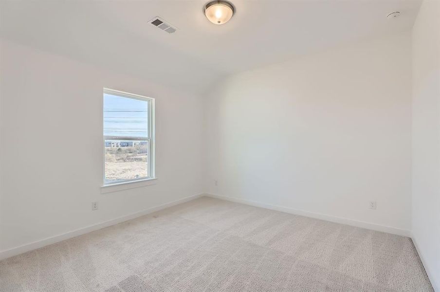 Carpeted empty room featuring vaulted ceiling