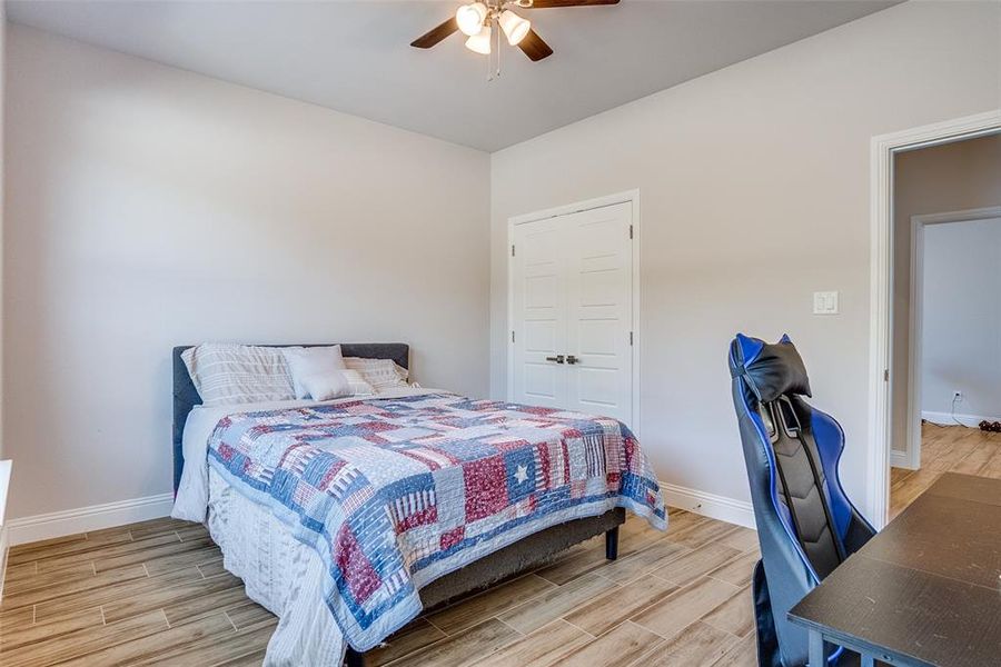 Bedroom featuring wood tiled floors, a ceiling fan, and a closet