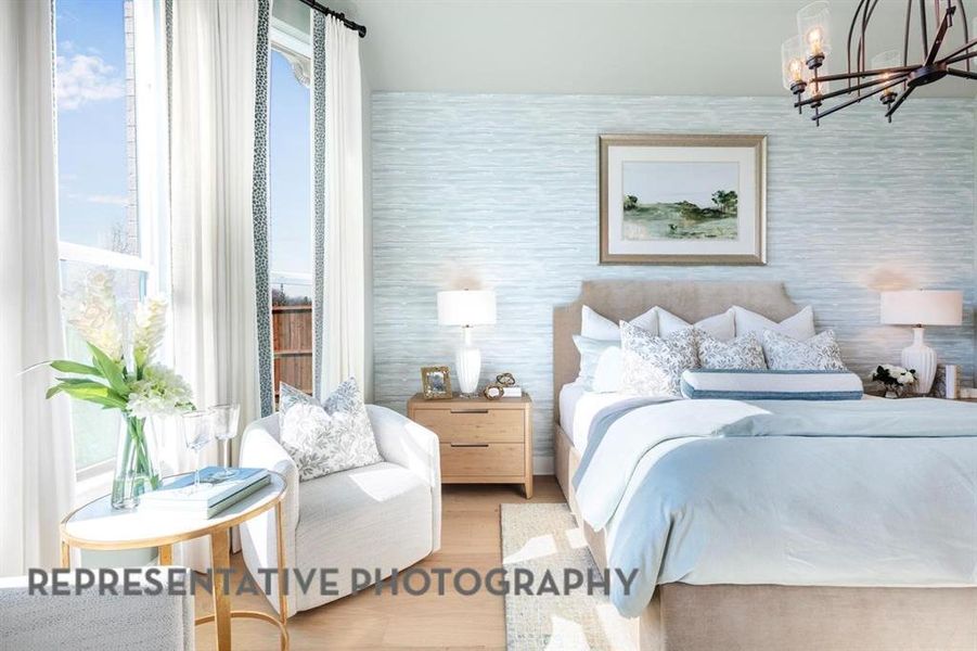 Bedroom with a chandelier, wood finished floors, and wallpapered walls