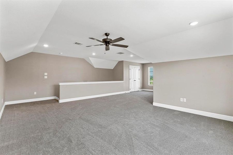 Additional living space featuring ceiling fan, vaulted ceiling, and carpet