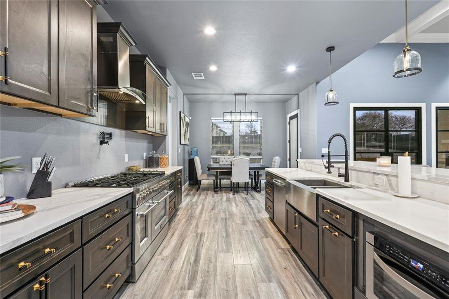 Kitchen with appliances with stainless steel finishes, light stone countertops, decorative light fixtures, light wood-style flooring, and recessed lighting