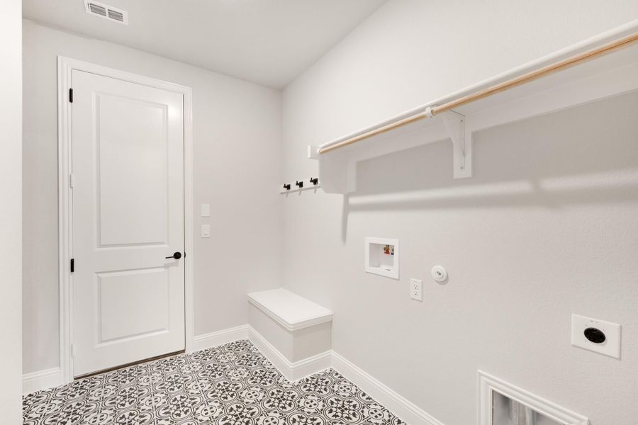Laundry or mudroom with patterned tile floor, wall hooks, built-in bench, and hanging rod Laundry or mudroom with patterned tile floor, wall hooks, built-in bench, and hanging rod