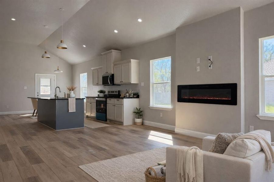 Kitchen featuring open floor plan, dark countertops, stainless steel appliances, a center island with sink, and pendant lighting