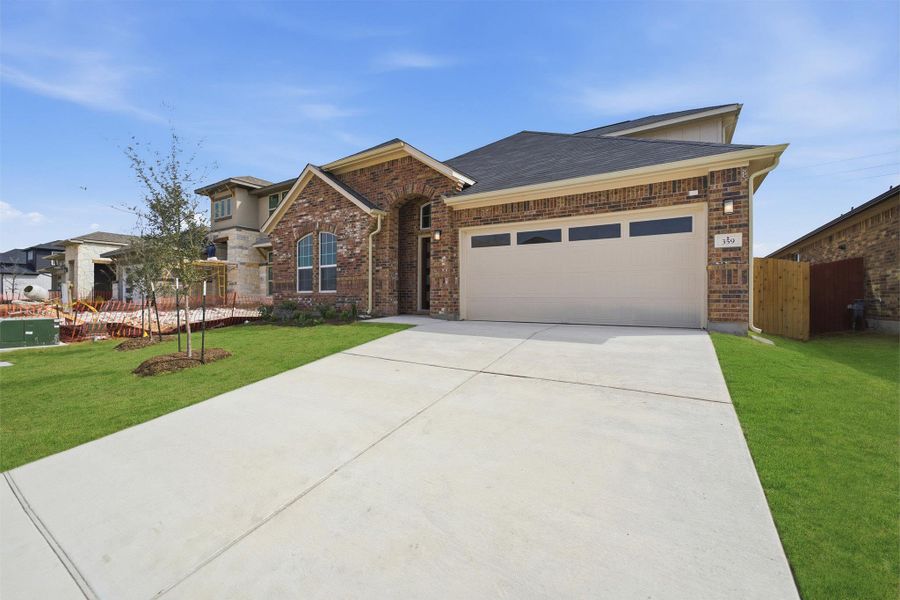 View of front facade featuring an attached garage, driveway, and brick siding