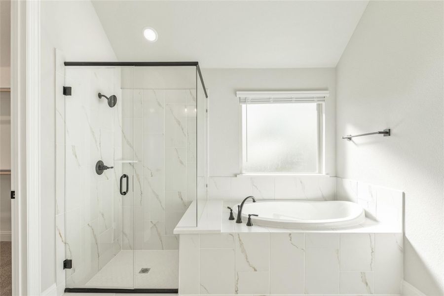 Master bathroom with marble-tiled soaking tub, glass-enclosed walk-in shower, and black fixtures Master bathroom with marble-tiled soaking tub, glass-enclosed walk-in shower, and black fixtures