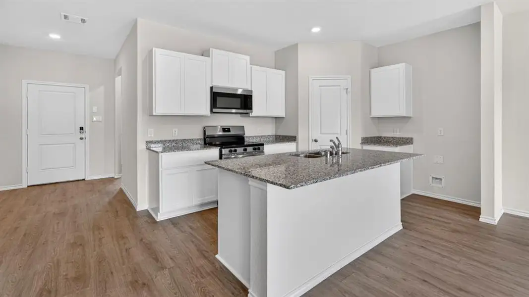 Kitchen featuring a central island with dual sinks, white cabinetry, granite countertops, and stainless steel appliances Kitchen featuring a central island with dual sinks, white cabinetry, granite countertops, and stainless steel appliances