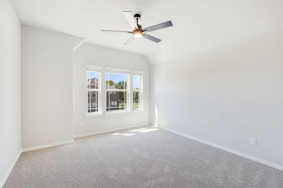 Empty bedroom with vaulted ceiling, ceiling fan, carpet flooring, and triple windows Empty bedroom with vaulted ceiling, ceiling fan, carpet flooring, and triple windows