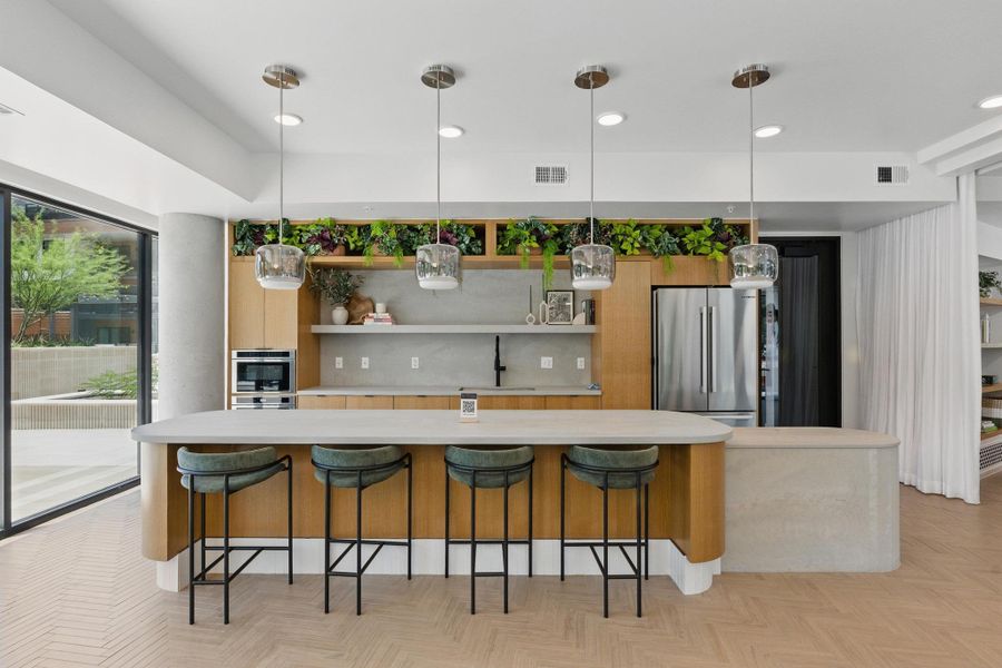 An inviting kitchen features a generously sized island with seating, a built-in oven, and a modern refrigerator.