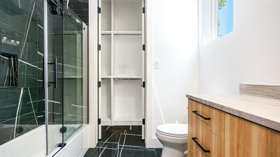 Full bathroom featuring shower / bath combination with glass door, vanity, toilet, and tile patterned flooring