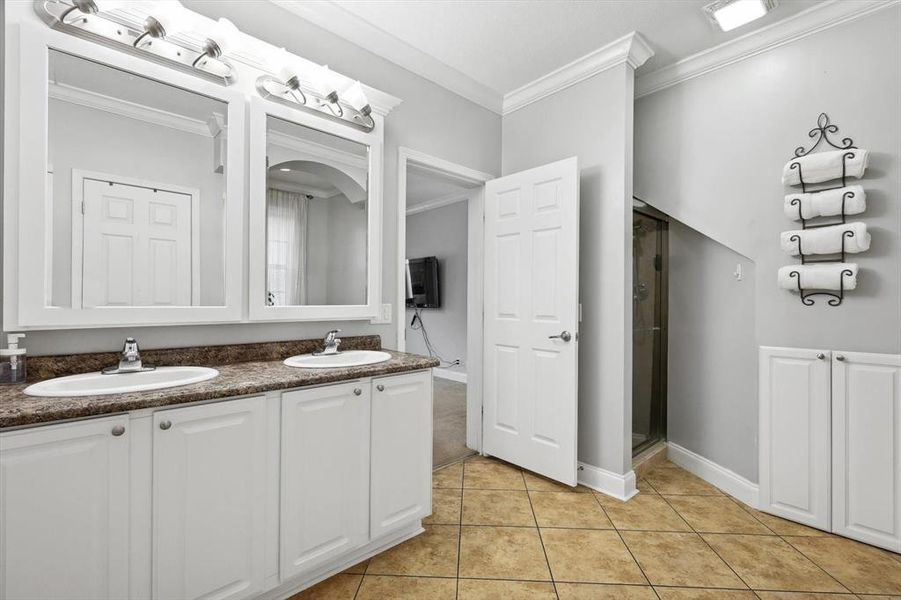 Bathroom featuring vanity, crown molding, a shower with door, and tile patterned floors