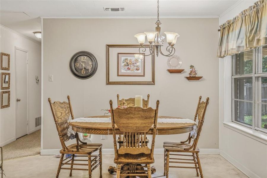 Dining area featuring light-toned walls, a multi-pane window, and a ceiling-mounted chandelier Dining area featuring light-toned walls, a multi-pane window, and a ceiling-mounted chandelier