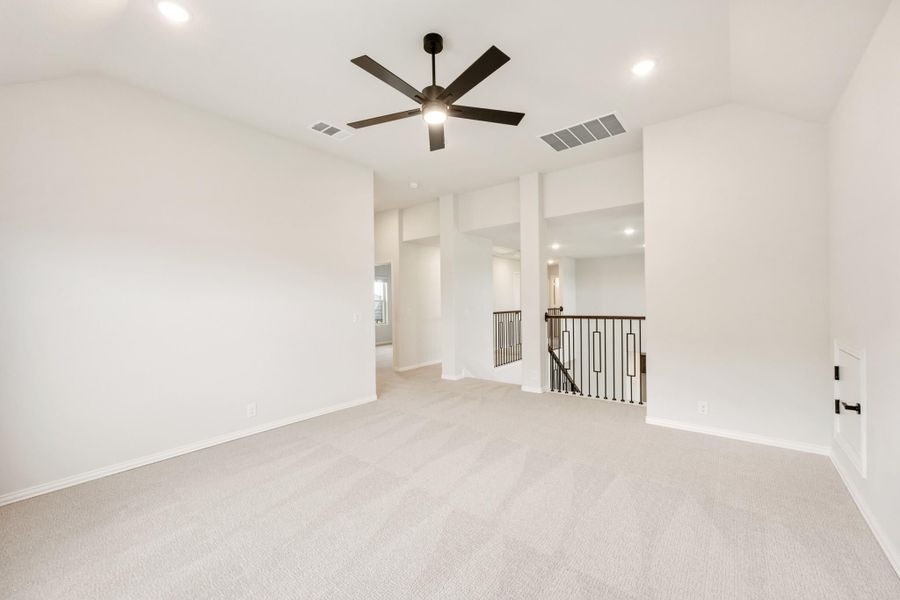 Open upstairs loft with carpet, ceiling fan, and iron stair railing overlooking lower level