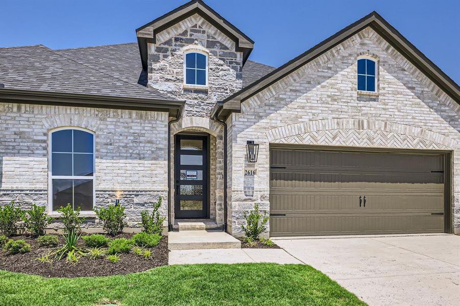 French country inspired facade with driveway, stone siding, and an attached garage French country inspired facade with driveway, stone siding, and an attached garage