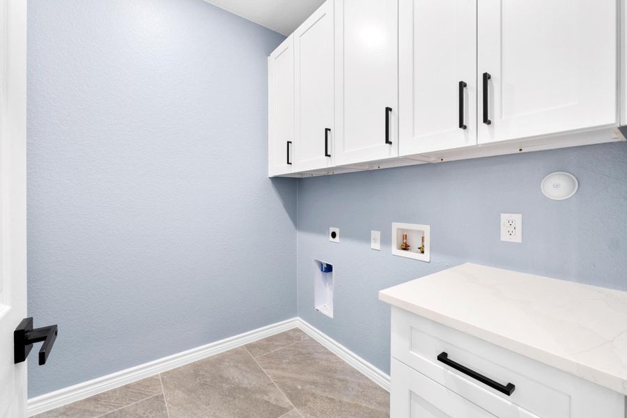 Washroom with cabinet space, hookup for a washing machine, electric dryer hookup, and a textured wall Washroom with cabinet space, hookup for a washing machine, electric dryer hookup, and a textured wall