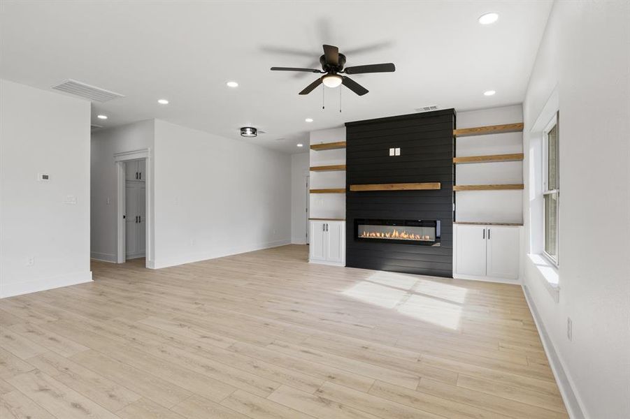 Unfurnished living room with ceiling fan, light wood-type flooring, recessed lighting, and a fireplace