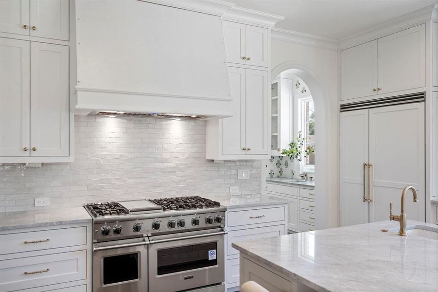 Kitchen with backsplash, custom exhaust hood, white cabinetry, and premium appliances