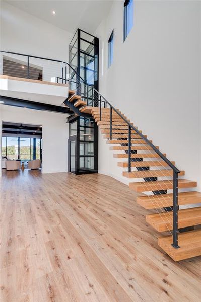 Stairway with hardwood / wood-style flooring and a towering ceiling