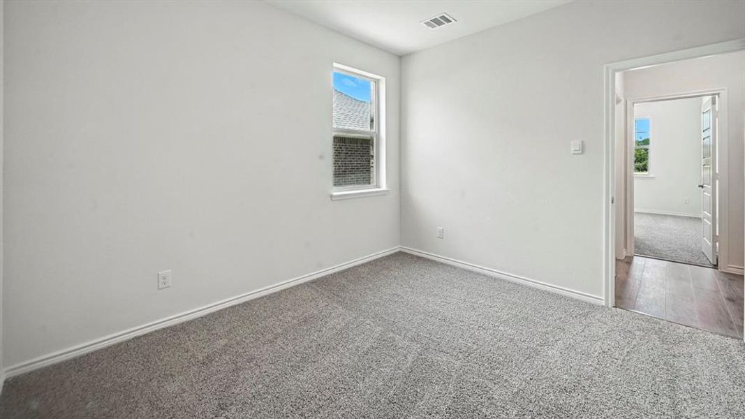 Bright room featuring light grey carpeting, white baseboards, and a window with white trim