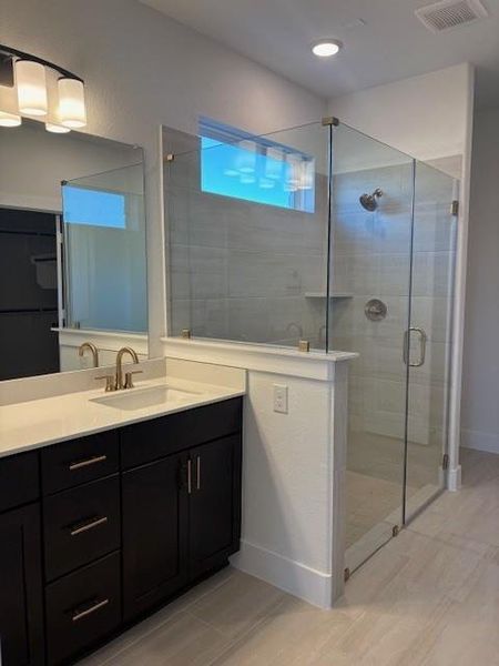 Full bathroom with a stall shower, vanity, and visible vents