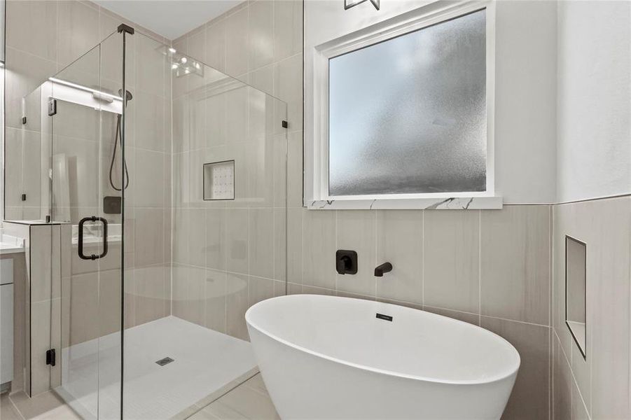 Full bathroom with a soaking tub, tile walls, and a shower stall