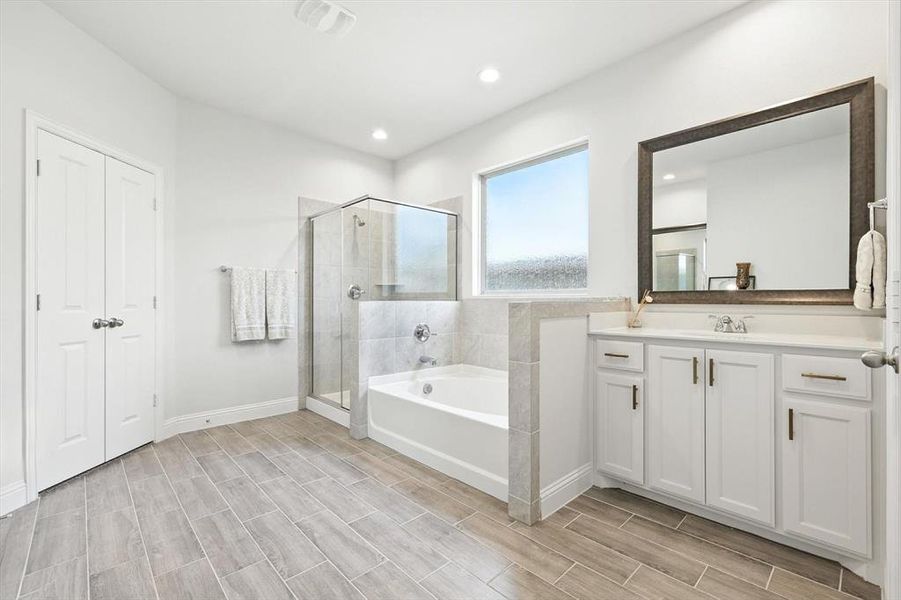 Full bathroom featuring a bath, a shower stall, vanity, wood finish floors, and recessed lighting