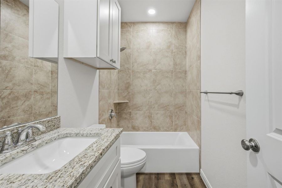 Modern bath features granite countertops and a tiled tub/shower combination, offering functional elegance.