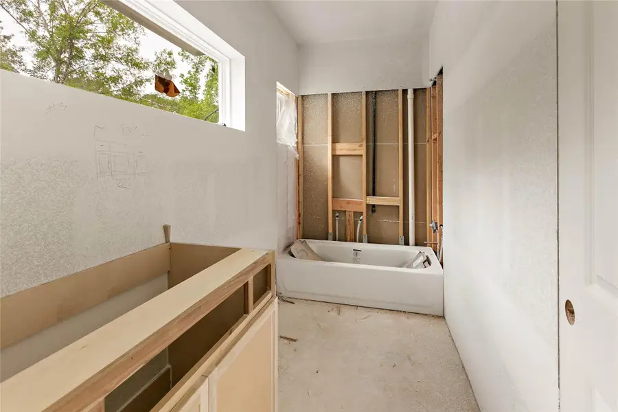 Natural light illuminates a full bath located upstairs, offering views of towering trees. Natural light illuminates a full bath located upstairs, offering views of towering trees.