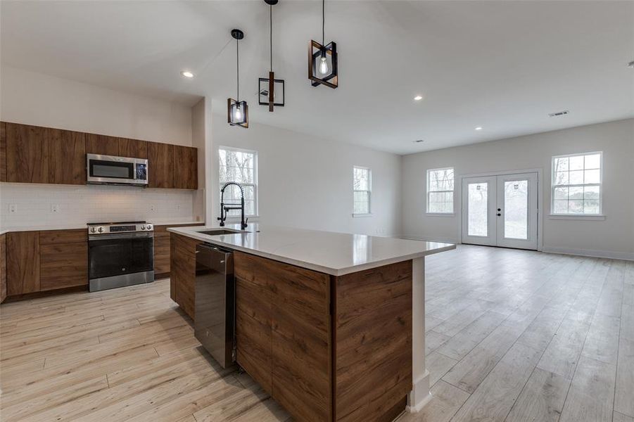 Kitchen featuring decorative backsplash, stainless steel appliances, modern cabinets, and a sink