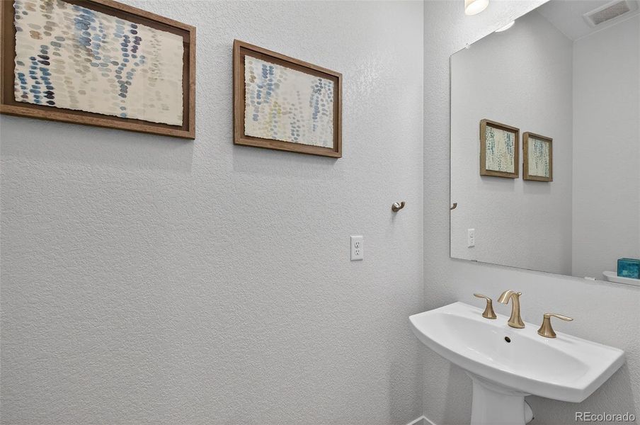 Powder Room – Elegant half bath finished with a pedestal sink, brushed-gold fixtures.