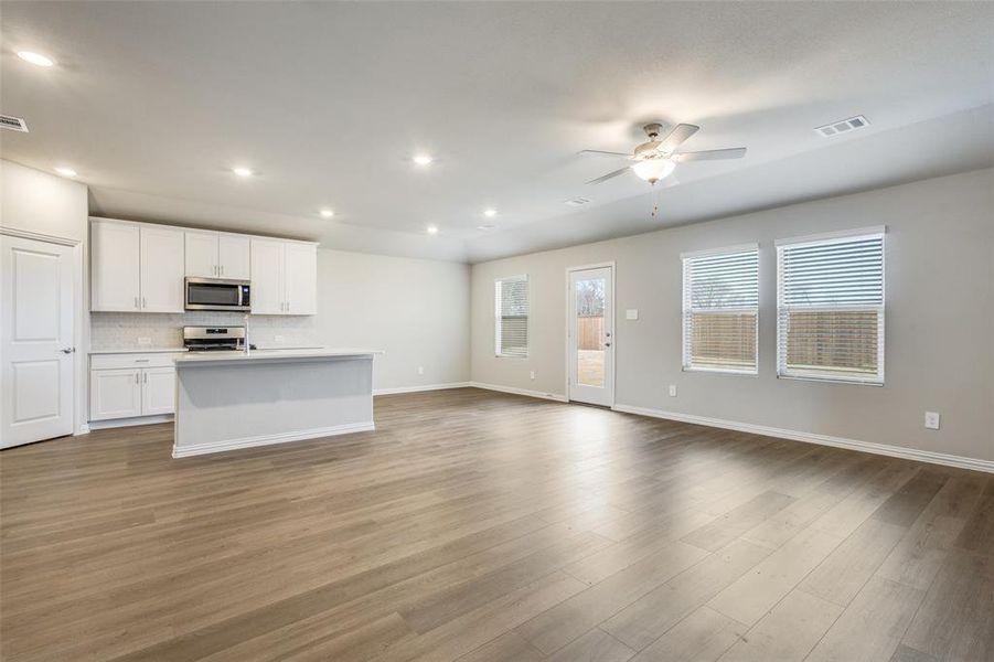 Kitchen featuring a center island with sink, white cabinets, open floor plan, tasteful backsplash, and recessed lighting